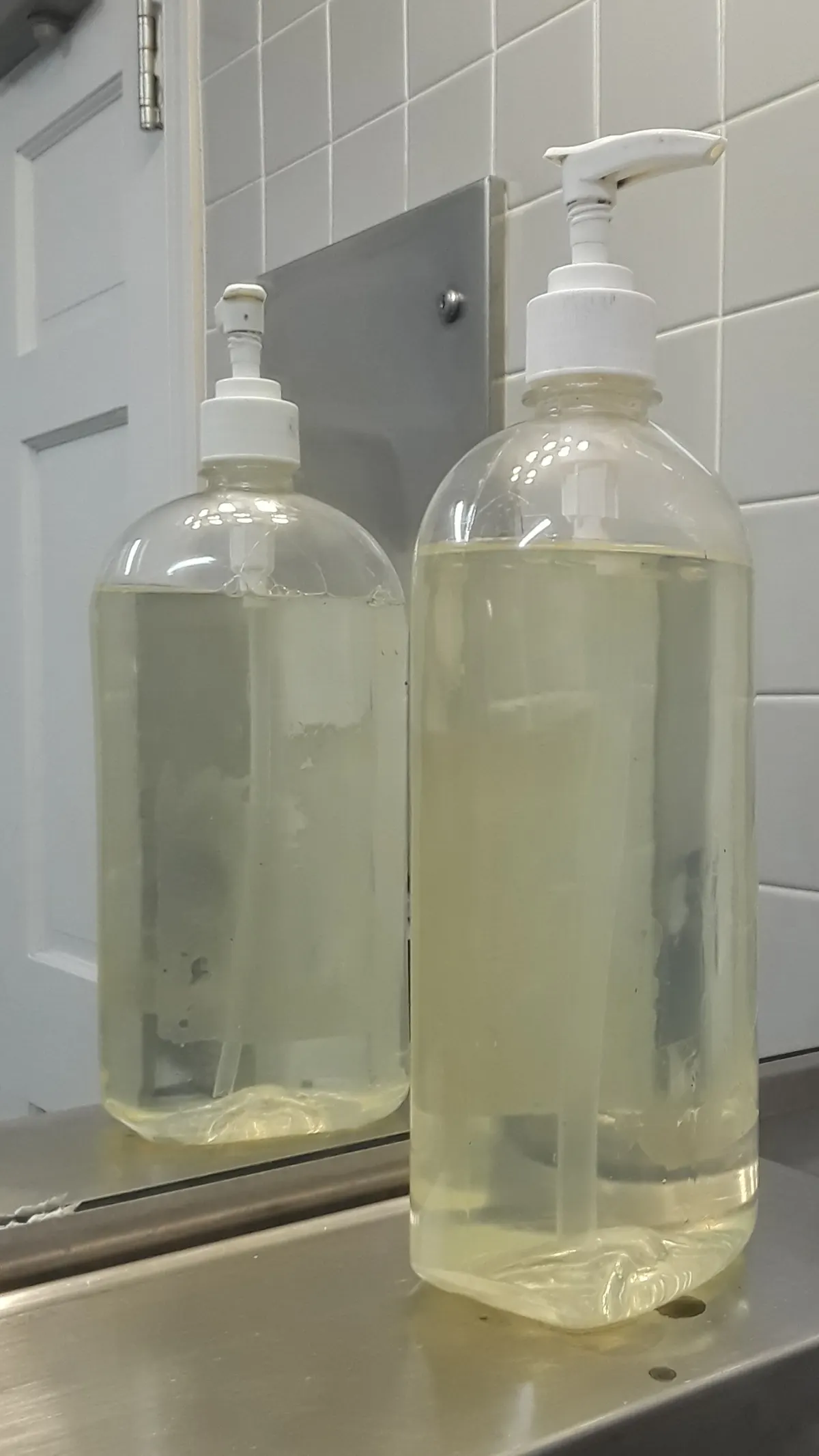 Two clear refillable pump bottles side by side