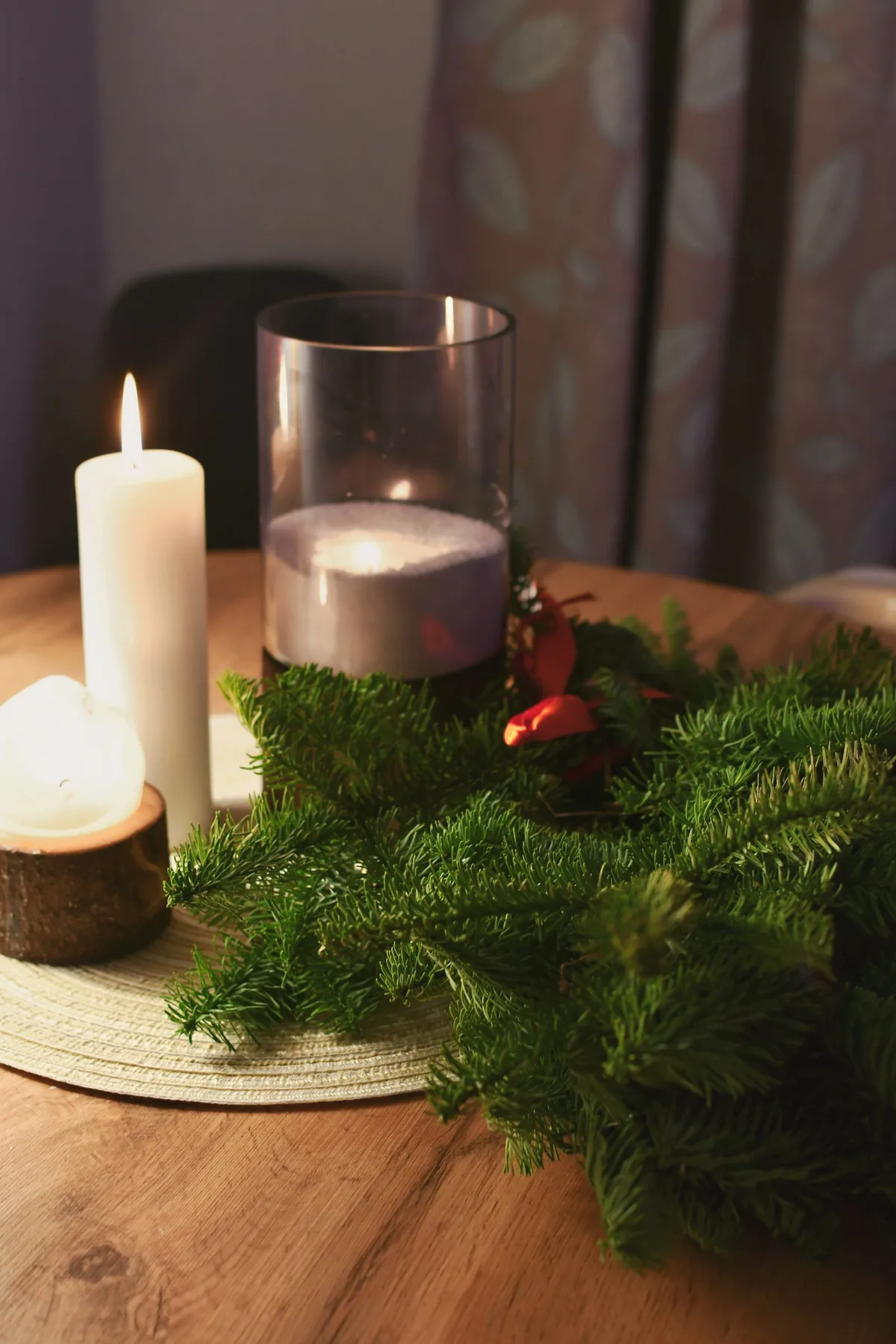 Christmas candles and evergreen sprigs on a wooden table