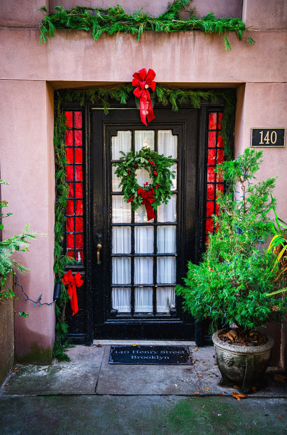 Front doorway decorated for Christmas with wreaths and evergreen garland