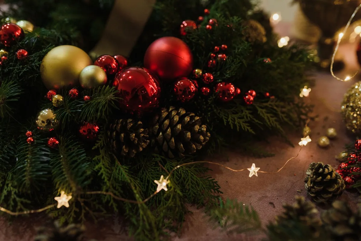 Christmas garland with pine cones, red and gold baubles, and star fairy lights on a table