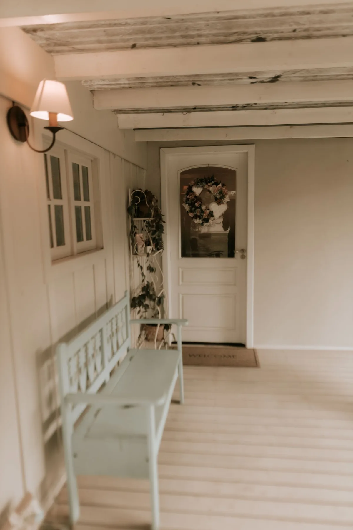 Bright entry hall with a white bench and a wreath on the front door
