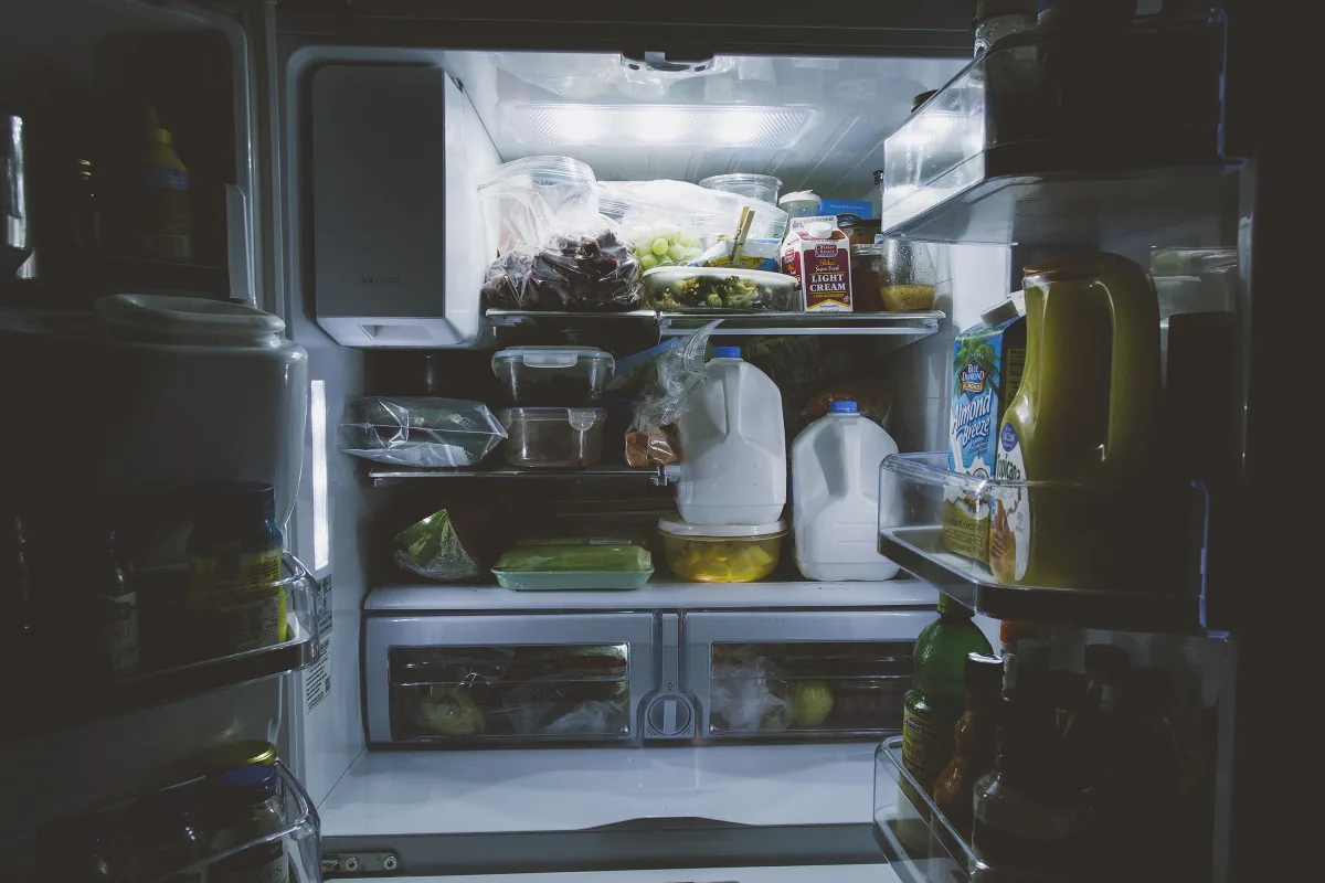 Open refrigerator with shelves of drinks, produce, and leftovers ready to sort into zones
