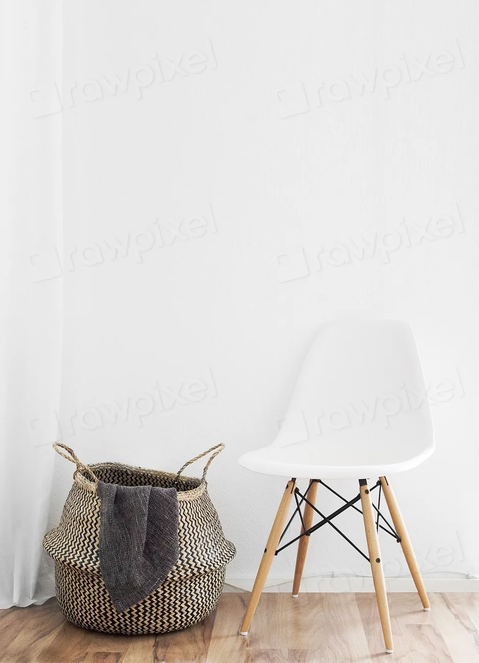 Woven laundry basket beside a chair in a minimal corner