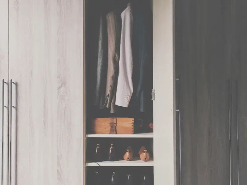 Tall wooden wardrobe with clothes hanging neatly inside