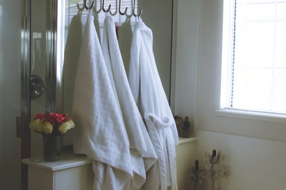White bathrobes hanging on hooks in a bright bathroom